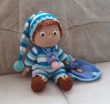 Amigurumi-Puppe mit gestreiftem Strampler, Schnuller, Zipfelmütze und blauem Kuscheltuch mit Bärengesicht