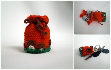 Gehäkeltes orangenes Täschchen mit Pilzmotiv, grünem Rand und braunem Zugband; daneben Süßigkeiten und Schlüssel.