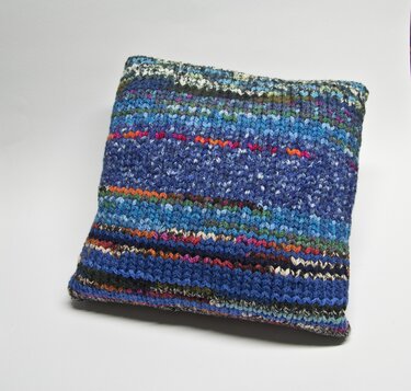 Gestrickter Kissenbezug in Blautönen mit bunten Streifen, frontal