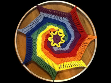 Gehäkelte Regenbogenspirale in Hexagon
Form auf Holz