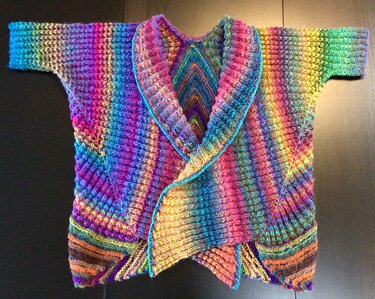 Flach ausgelegte, gestrickte Damen-Weste in Regenbogenfarben mit breitem Schalkragen und kurzem Ärmel.