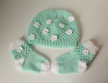 Gestricktes mintgrünes Baby-Set mit Mütze und Söckchen und weißen Blumenapplikationen