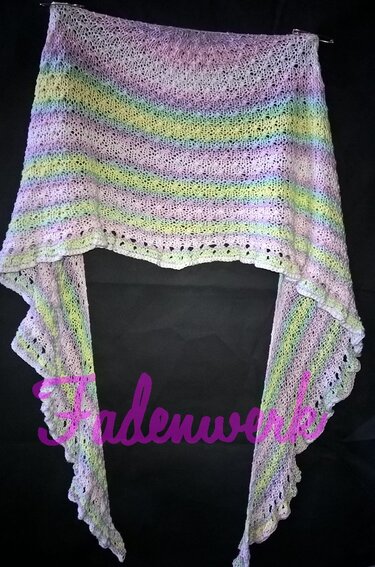 Gestricktes halbrundes Tuch in Pastellstreifen mit Lochmuster vor dunklem Hintergrund