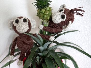 Zwei gehäkelte braun-beige Amigurumi-Affen in einer Topfpflanze
