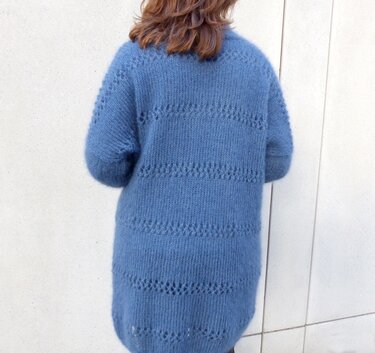 Rückenansicht einer Damenjacke: lange, blaue Strickjacke mit durchbrochenem Ajourmuster.