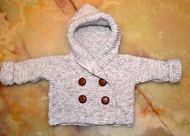 Schlichte gestrickte Babyjacke mit Kapuze, vier braunen Knöpfen und umgeschlagenen Ärmeln