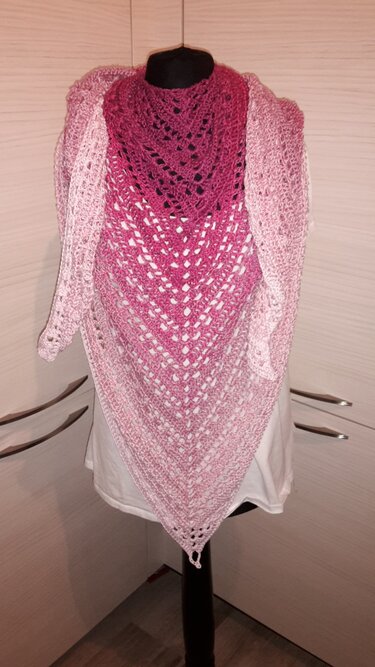 Gehäkeltes Dreieckstuch in Pink- und Rosatönen mit Lochmuster, drapiert auf einer Anziehpuppe.