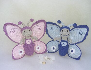 Zwei gehäkelte Amigurumi-Schmetterlinge nebeneinander, einer rosa-lila, einer blau-türkis