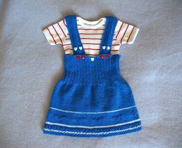 Blaues gestricktes Baby-Trägerkleid mit roten und weißen Herzknöpfen und gestreiftem Kurzarmshirt