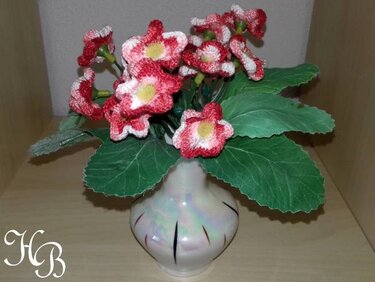 Romantisches Bouquet aus handgehäkelten roten und weißen Blumen in einer Keramikvase