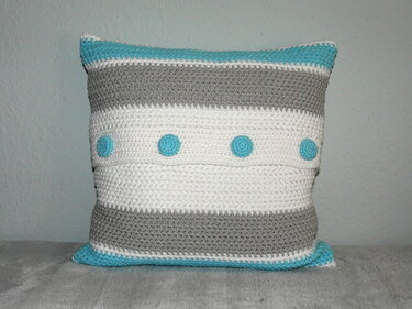 Quadratisches gehäkeltes Kissen mit grauen und weißen Streifen und vier türkisen Punkten