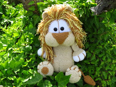 Gehäkelter Amigurumi-Löwe mit gelb-brauner Garnmähne sitzt im Efeu