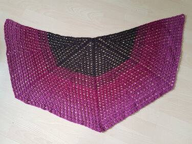 Gehäkeltes Dreieckstuch in Anthrazit und Magenta mit offenem Lochmuster auf hellem Boden