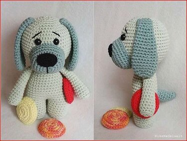 Gehäkelter Amigurumi-Hund in Creme und Hellblau mit schwarzer Nase und zwei bunten Häkelkreisen