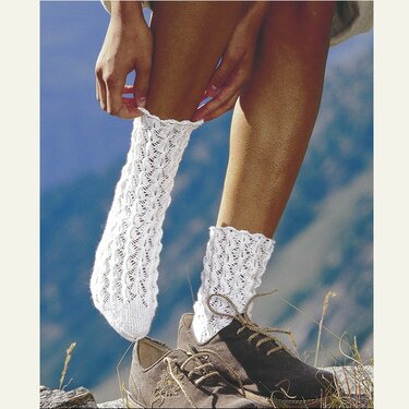 Nahaufnahme weißer, gestrickter Kurzsocken mit Ajourmuster an Damenbeinen