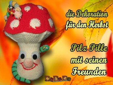 Häkelpilz mit roter Kappe und weißen Punkten, großen Augen und zwei kleinen Häkelwürmchen