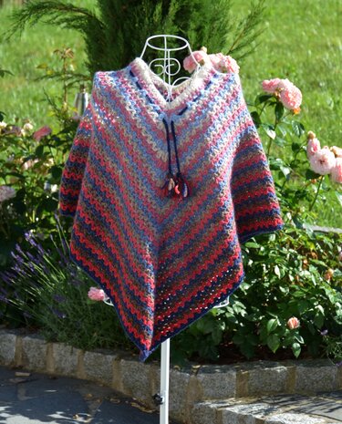 Gehäkelter gestreifter Poncho mit V-Ausschnitt und Kordelzug auf Drahtpuppe im Garten