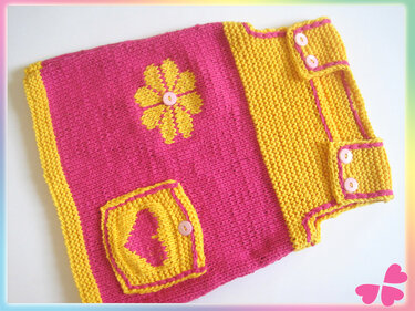 Gestrickte Babyweste in Pink und Gelb mit gelber Blume und Herztasche