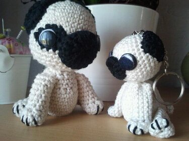 Zwei gehäkelte Mops‑Amigurumi in Creme und Schwarz, eine mit Schlüsselring