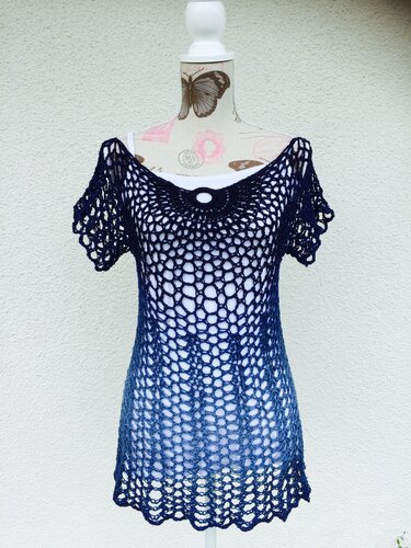 Blaue Häkel‑Tunika im Ombre‑Look auf Schneiderpuppe, offenes Netzmuster, kurzer Ärmel, rundes Ringdetail