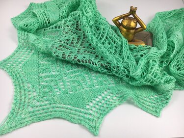 Mintgrünes gestricktes Dreieckstuch mit Ajourmuster und gezackter Kante, neben einer kleinen Deko-Froschfigur drapiert