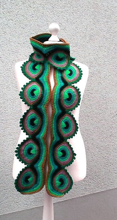 Gehäkelter grüner Schal mit kreisförmigen, gestaffelten Motiven auf einer Schaufensterpuppe