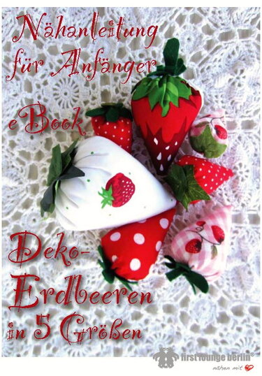 Handgenähte Stoff‑Erdbeeren in verschiedenen Größen und Mustern auf einem gehäkelten Deckchen.