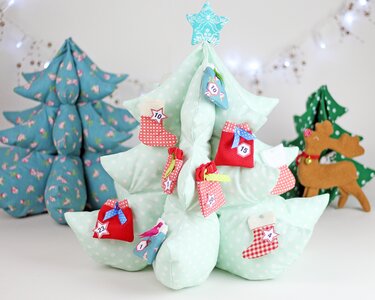 Stoff-Adventskalender in Baumform aus hellgrünem Punktestoff mit kleinen, nummerierten roten und blauen Säckchen und Stiefeln