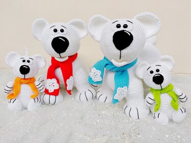 Four white crocheted amigurumi bears with black noses and colorful scarves on a snow-like background