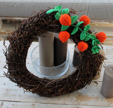 Kranz aus Zweigen mit gehäkelten orangefarbenen Beeren und grünen Blättern