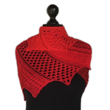 Red crochet dragon tail scarf with lace mesh and scalloped points draped on a black mannequin