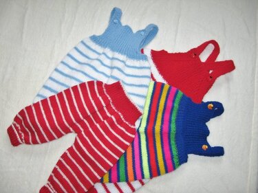 Gestrickte Babyhosen und Strampler mit Trägern und Knopfbefestigung in unterschiedlichen Streifenmustern