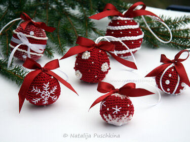 Gruppe roter, gehäkelter Weihnachtskugeln mit weißer Stickerei und roten Schleifen