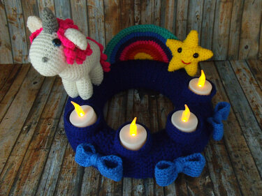Dunkelblauer, gehäkelter Adventskranz mit Einhorn, Regenbogen, Stern und vier LED-Teelichtern