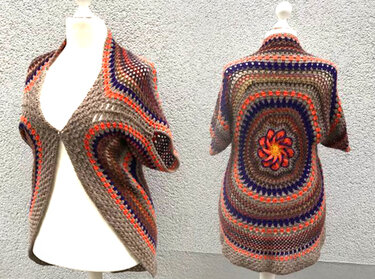 Vorder- und Rückansicht eines gehäkelten Seelenwärmers mit Mandala-Rundmuster in Braun, Grau, Orange und Dunkelblau, mit kurzen Ärmeln auf einer Schneiderpuppe