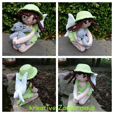 Gehäkelte Amigurumi-Fee in Hellgrün mit Hut und weißen Flügeln, die einen kleinen grauen Teddybären hält.