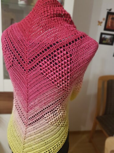 Nahaufnahme eines gehäkelten Dreieckstuchs mit Mittelzunahme, Stäbchen- und Lochmuster in Pink zu Gelb