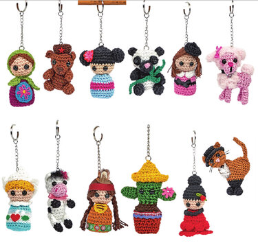 Zwölf bunte Amigurumi‑Schlüsselanhänger mit Schlüsselringen auf weißem Hintergrund.