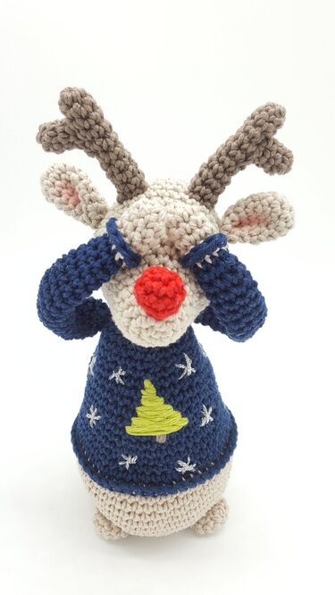 Gehäkeltes Rentier‑Amigurumi mit roter Nase und blauem Weihnachtspullover, Augen mit Ärmeln bedeckt