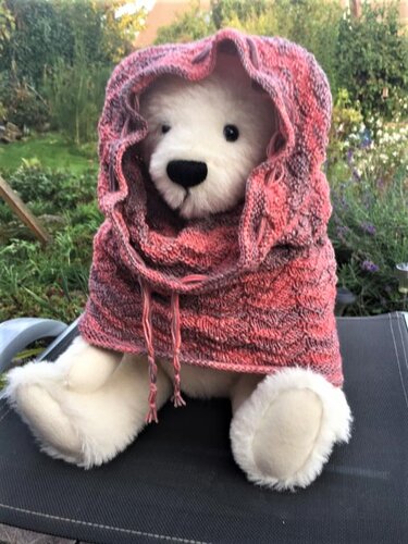 Weißer Teddybär trägt rosa-melierten gestrickten Scoodie mit Kapuze und Kordelzug