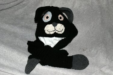 Gehäkelte schwarze Mütze mit Hundegesicht, weißer Schnauze und grauen Ohren.