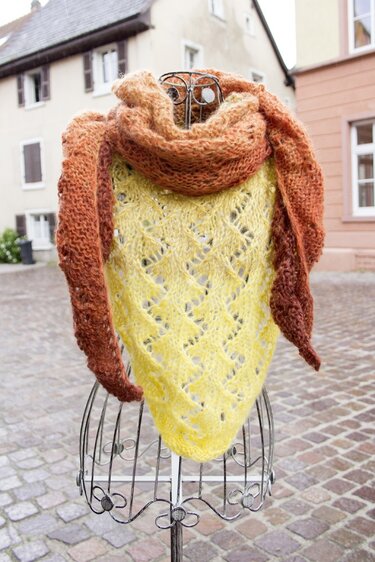 Drahtbüste mit gelbem gestricktem Dreieckstuch im Ajourmuster und braun-orange verlaufendem Tuch