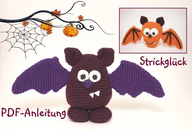 Gehäkelte Fledermaus in dunkelrot mit lila Flügeln und sichtbaren Zähnen vor Halloween-Dekor