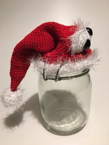Einmachglas mit roter gehäkelter Weihnachtsmütze mit weißem, flauschigem Rand und Bommel