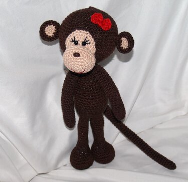Gehäkelter brauner Amigurumi-Affe mit beiger Schnauze und roter Schleife