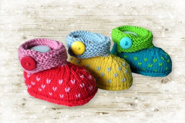 Three colorful newborn knit booties with rolled cuffs and buttons