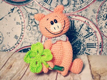 Rosa Amigurumi-Glücksschwein mit grünem Kleeblatt und silberner Schleife
