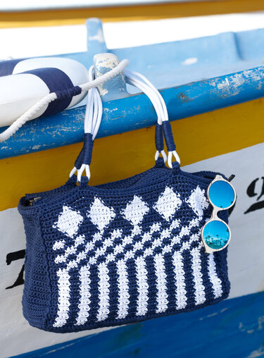 Gehäkelte blau-weiße Henkeltasche mit Rauten- und Streifenmuster und weißen Kordelgriffen