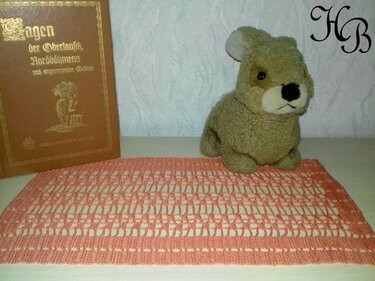 Rechteckiges gehäkeltes Deckchen in Koralle mit Lochmuster auf hellem Untergrund