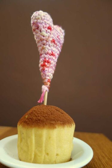 Cupcake mit gehäkeltem Herz-Topper aus pastellfarbenem Garn auf Zahnstocher
